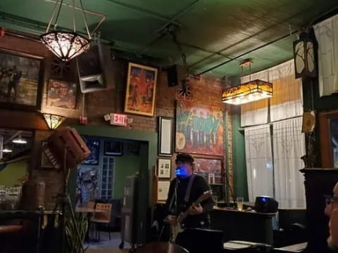 a person playing a guitar in a room with tables and chairs