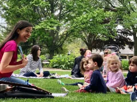 a person and a group of children sitting on the grass