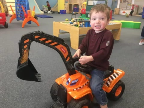 a boy sitting on a toy tractor