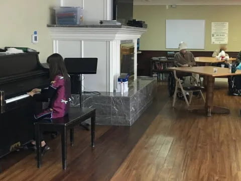 a group of people sitting in a room with a piano