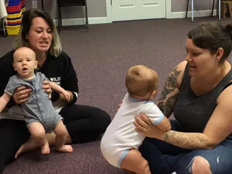 a group of people sitting on the floor with a baby