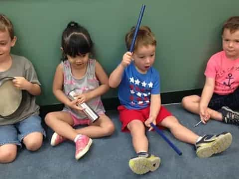 a group of kids sitting on the floor with bats