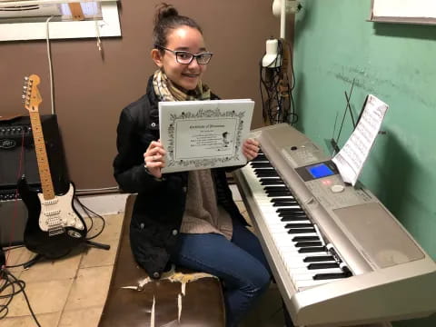 a person holding a sign and sitting at a piano