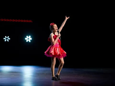 a person in a red dress on stage with the arms up