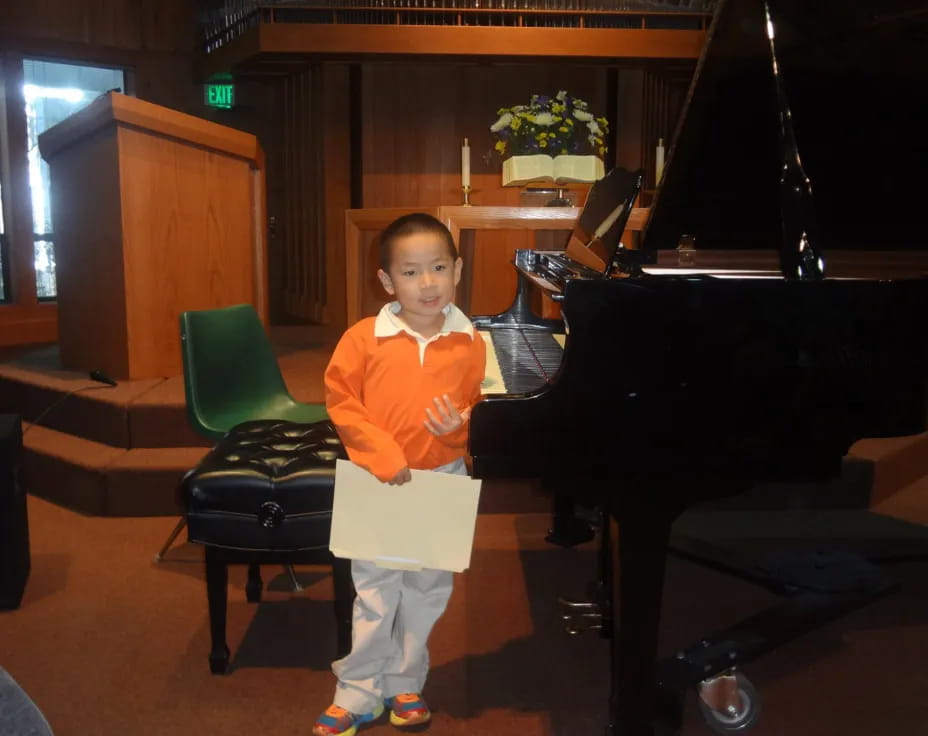 a boy standing in front of a piano