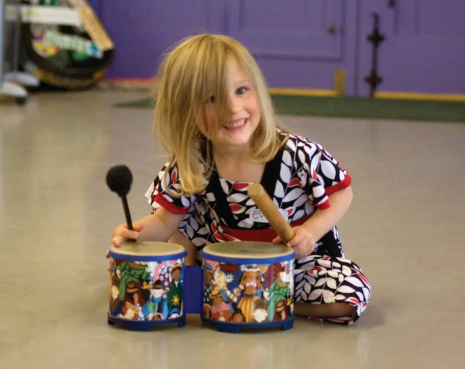 a girl sitting on the floor with a bucket of paint