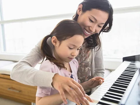 a woman and a child playing a piano