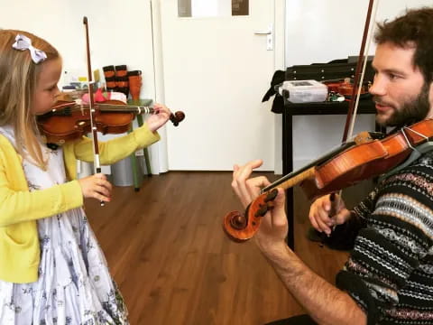 a person playing a violin next to a girl