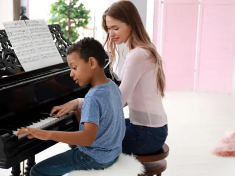 a woman and a boy playing a piano