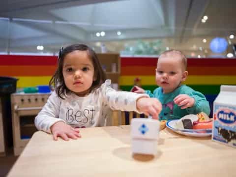 a couple of children sitting at a table with a toy
