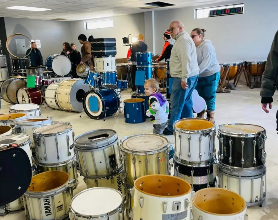 a group of people standing around a table with drums