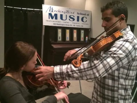 a man playing a violin next to a woman playing a violin