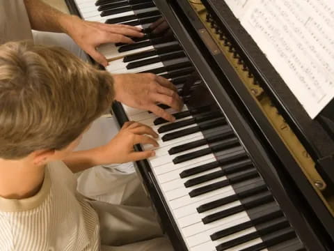 a person playing a piano with a young boy