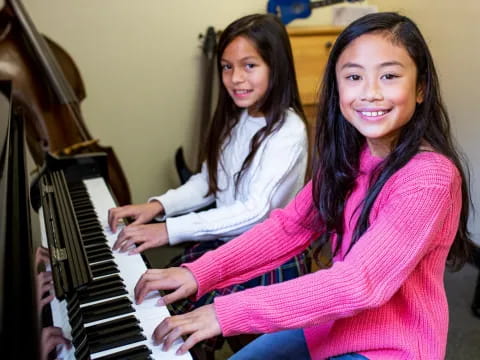 a couple of girls playing a piano