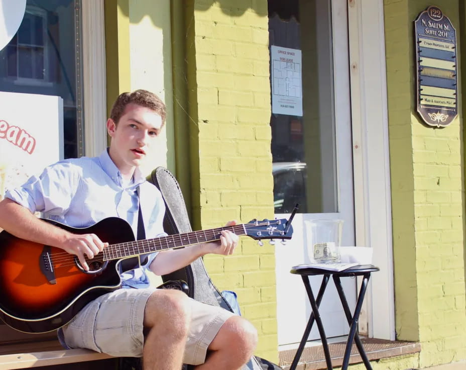 a person sitting on a stool playing a guitar