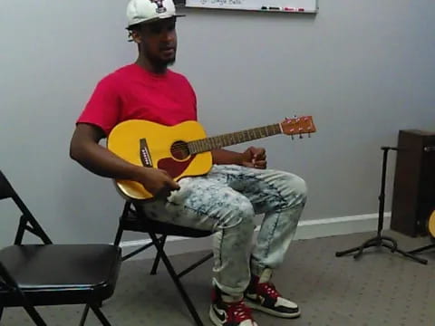 a man sitting on a chair playing a guitar