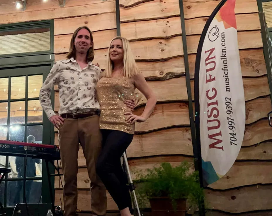 two women standing next to a surfboard