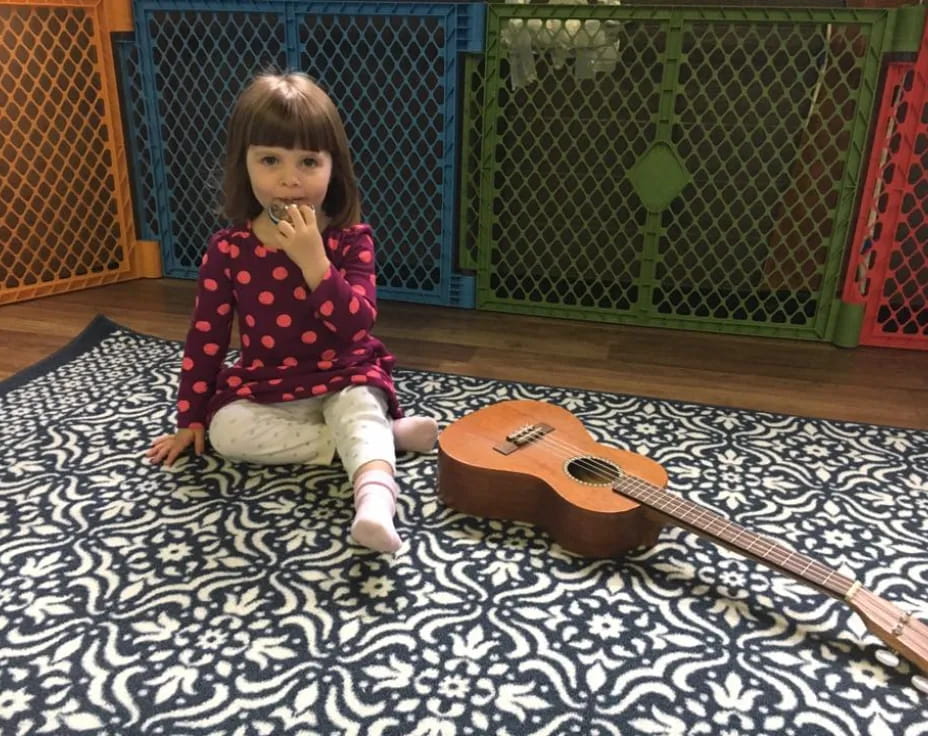 a girl sitting on the floor next to a guitar