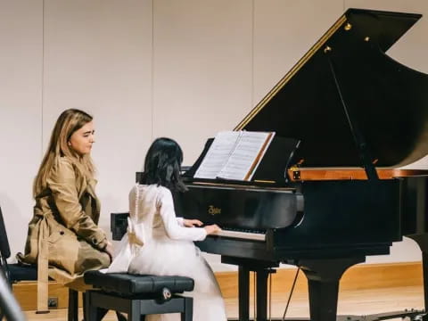 a person playing a piano with a young girl sitting on the side