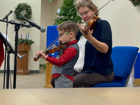 a person playing a violin next to a boy playing a violin