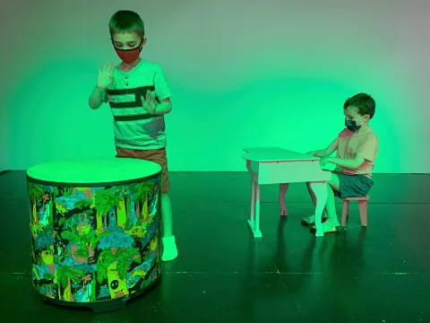 a couple of kids wearing masks and standing next to a table