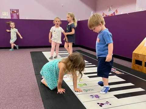 a group of children playing on a mat in a room with purple walls