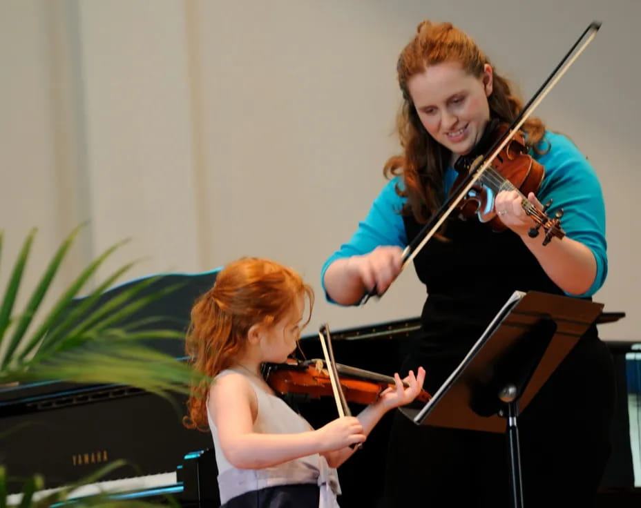 a person playing a violin next to a young girl