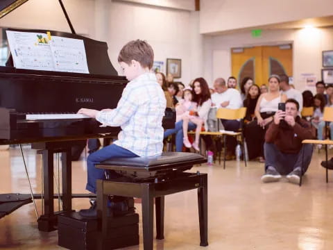 a boy playing a piano in front of a group of people
