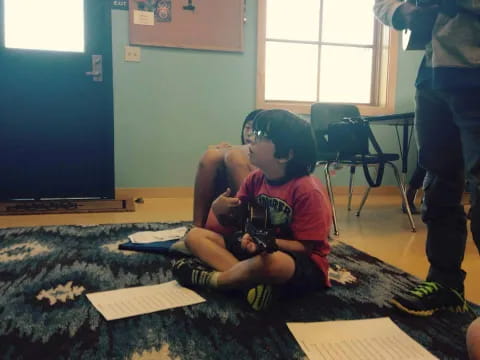 a boy sitting on the floor with a camera in his hand