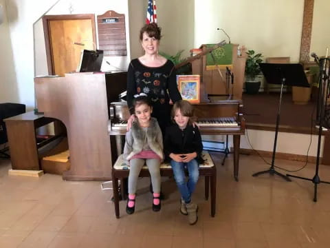a group of kids sitting on a bench in front of a piano