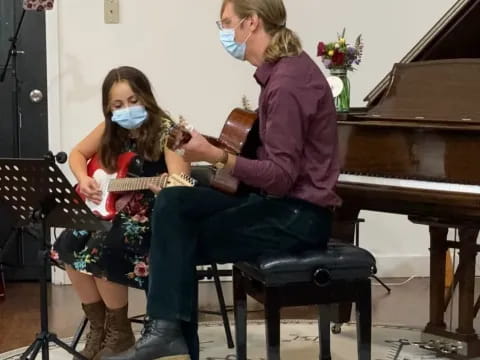 a person sitting on a chair with a girl in a mask