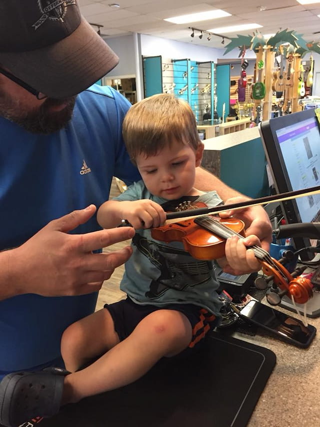 a person playing a violin with a young boy
