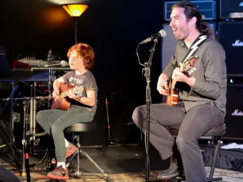 a person and a boy playing guitars