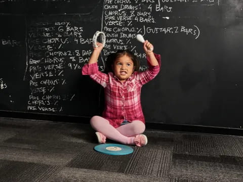 a child playing with a frisbee in front of a chalkboard