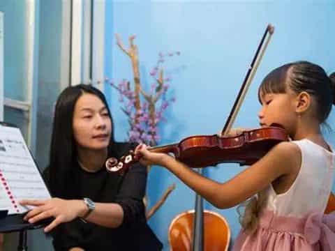 a person playing a violin next to a girl playing a piano