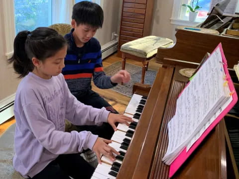 a boy and girl playing piano