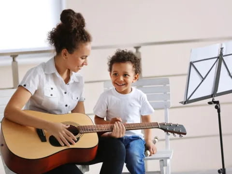 a person and a child playing a guitar