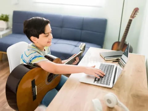 a person playing a guitar and a laptop