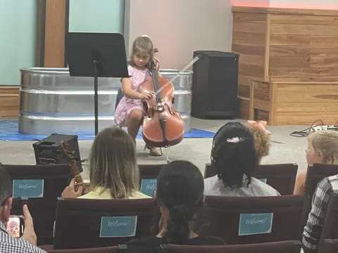 a girl playing a violin in front of a group of people