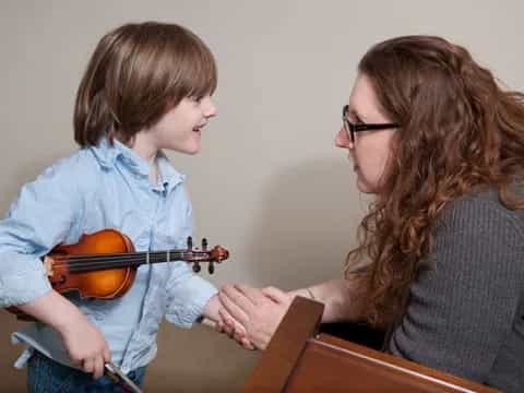 a person playing a violin to a young boy