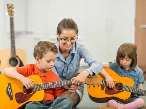 a person and two boys playing guitars