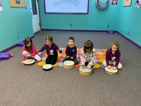 a group of children sitting on the floor with their feet on bowls
