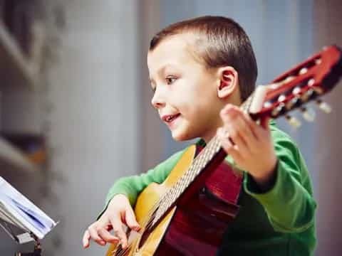 a young boy holding a red and black guitar