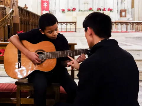 a man playing a guitar next to another man