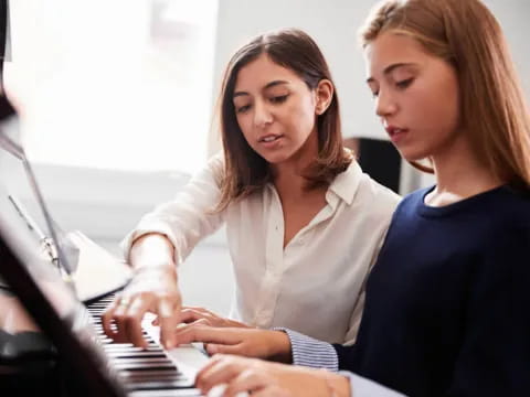 a couple of women sitting at a piano