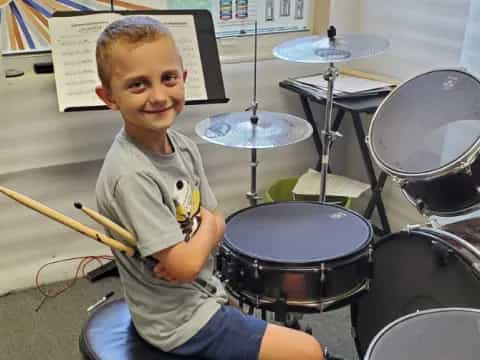 a boy sitting in front of a drum set