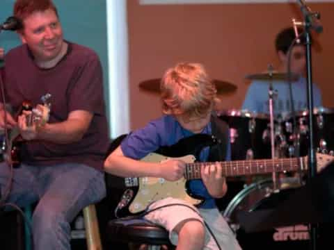 a man playing guitar next to a man playing a guitar