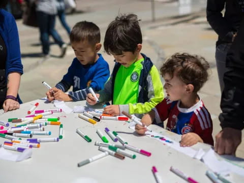 a group of boys sitting at a table with colored pencils