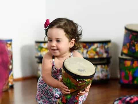 a little girl holding a drum