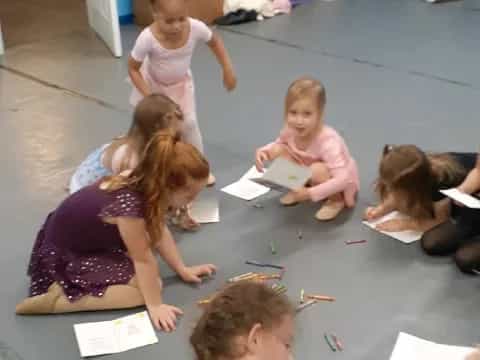 a group of children sitting on the floor writing on paper